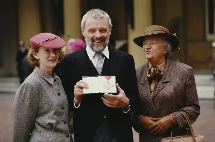 Сър Антъни Хопкинс получава CBE (орден на командир в Британската империя) в Бъкингамския дворец в Лондон, 3 ноември 1987 г. Той е придружен от съпругата си Дженифър и майка си Ани.