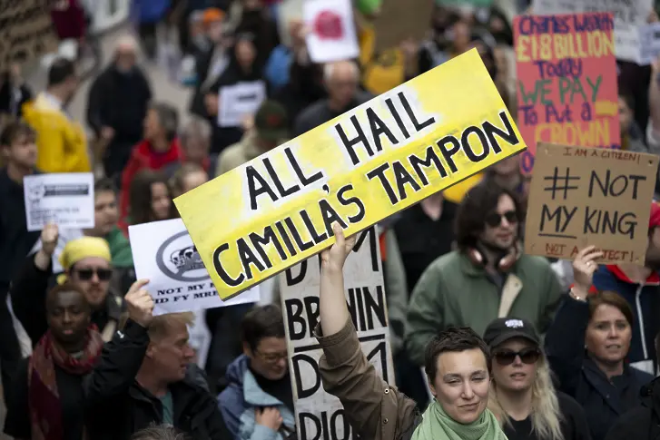 Жена държи табела протестна табела с надпис "Да живее тампонът на Камила" по време на протест срещу коронацията