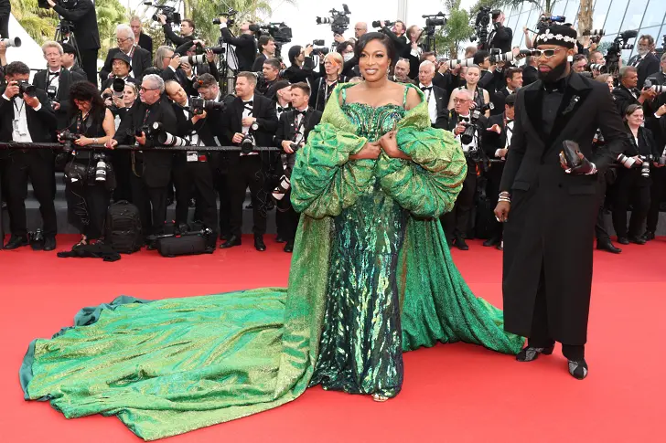Нигерийската актриса Чика Айк се появява в изумруденозелена в тон на бижута рокля и обемно преливащо се наметало от нигерийския лейбъл Kud Collections.
